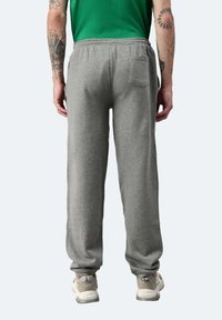Graue Jogginghose mit schmal zulaufendem Design, elastischem Bund und sichtbarem Seitentasche. Der Stoff wirkt weich mit einer dezenten Textur.