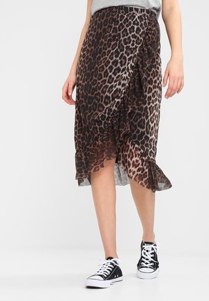 Kvinde iført en brun og sort leopardmønstret flæset nederdel og sorte høje sneakers, der går på en hvid gulv.