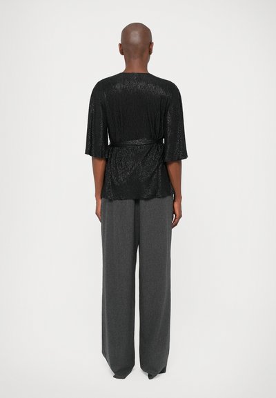 Haut noir texturé avec une taille ceinturée et des manches larges, associé à un pantalon large à taille haute gris. Tissu lisse avec une coupe décontractée.
