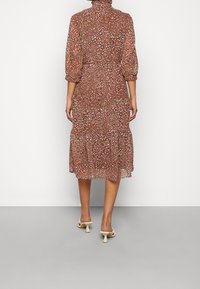 Braun gemustertes Midi-Kleid mit Blumen, hohem Kragen und Puffärmeln, das einen gestuften Rock und leichten, durchsichtigen Stoff aufweist.
