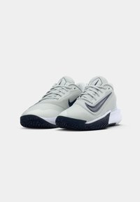 Pair of light gray athletic shoes with dark gray Nike swoosh logos, white midsoles, and black textured outsoles, facing forward on white background.