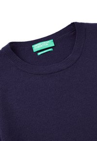 Tmavě modrý svetr vyrobený z italské merino příze. Má kulatý výstřih a žebrované okraje. Obsahuje zelenou etiketu s názvem značky.