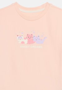 Ροζ ανοιχτό πουκάμισο με τρεις κινούμενες γάτες — η μία κοιμάται με μάσκα, η άλλη ροζ χαμογελά, η τρίτη μωβ χαμογελά — πάνω από το κείμενο «SWEET DREAMS» με αστέρια.