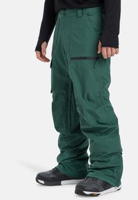Pantaloni da neve impermeabili verdi con tasche cargo, chiusura con zip e orli rinforzati. Il materiale è liscio, con una finitura leggermente lucida.