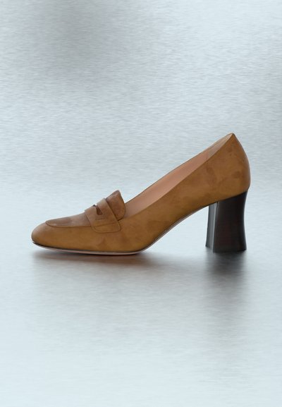 Escarpin pour femmes en daim marron avec un talon carré et une bride décorative traversant le cou-de-pied, présenté sur une surface gris clair.