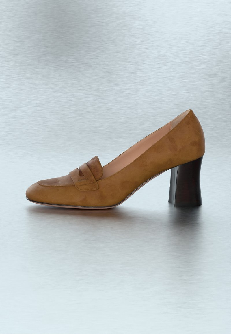 Escarpin pour femmes en daim marron avec un talon carré et une bride décorative traversant le cou-de-pied, présenté sur une surface gris clair.