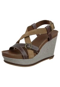 Sandale à talon compensé en suédine et cuir marron avec des straps entrecroisés, tissu à motif chevrons sur le talon et un détail de semelle cousue.