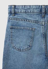 Jeans en denim bleu clair présentant une seule poche arrière avec couture contrastée, une texture légèrement décolorée et un design classique à cinq poches.