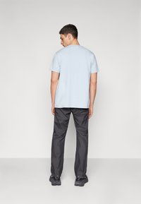 Light blue short-sleeve t-shirt paired with dark gray lightweight pants. The outfit has a simple design and textured fabric. Black footwear visible.
