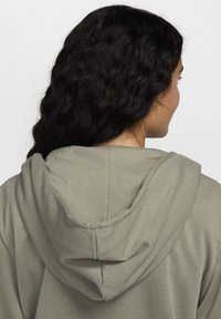 Olivenfarget hettegenser med en myk tekstur, med snor i hetta og sømdetaljer på baksiden, glatt stoffdesign.