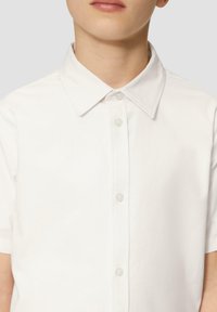 Biała koszula zapinana na guziki z kołnierzykiem, z krótkimi rękawami i gładką fakturą. Posiada przezroczyste plastikowe guziki oraz dopasowany krój.