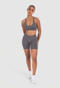 Grey sports bra and matching high-waisted shorts, made from smooth, stretchy material. Designed for active wear with a fitted silhouette.