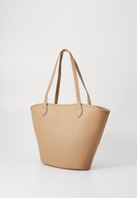 Τατα νάτσα τσάντα από συνθετικό υλικό σε καφέ απόχρωση με υφή, στρογγυλό σχήμα και δύο μακριές λαβές. Μινιμαλιστικός σχεδιασμός χωρίς ορατό υλικό ή διακοσμητικά στοιχεία.