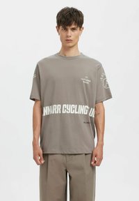 Grå kortermet t-skjorte laget av bomull, med hvite tekstgrafikker "ANNARR CYCLING" og "LA FLAMME ROUGE" på fronten og ermet.