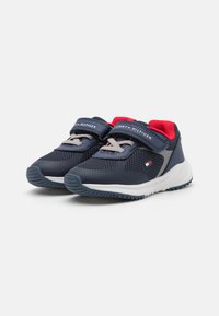 Scarpe da atletica navy con tomaia in mesh, cinturini grigi, accenti rossi e suole in gomma testurizzata. Presentano un sistema di chiusura a strappo per una facile vestibilità.