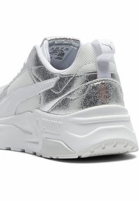 Weißer Sneaker mit metallisch silbernen Akzenten, strukturiertem Mesh- und synthetischem Obermaterial, ausgestattet mit einer gepolsterten weißen Sohle und einem gebrandeten Logodetail.