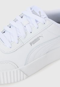 White Puma sneaker with white laces and silver Puma logo on the side and tongue, showing stitching and textured sole.