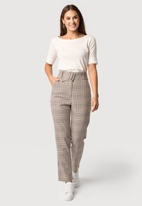 Beige hoge taille geruite broeken met een riem, rechte pijp ontwerp en zakken. Gecombineerd met een witte T-shirt met korte mouwen en witte sneakers.