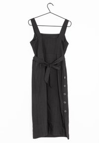 Musta hihaton mekko neliönmuotoisella pääntiellä, vyötäröllä vyö ja sivussa kuusi napinläpeä. Teksturoitu kangas.