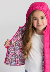 Gilet imbottito rosa con cappuccio caratterizzato da un interno colorato e fantasia. La fodera include cuori, arcobaleni e forme astratte.