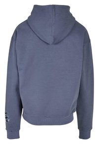 Grå hettegenser med cropped design, ribbestrikkede mansjetter og et svart kattedesign på venstre erme. Myk tekstur, avslappet stil.