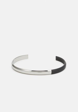 Open-ended cuff bracelet with a polished silver half and a matte black half on a white background.