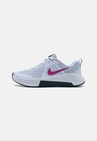 Nike idrettssko i hvit mesh med lilla logo, teksturerte sider og svart gummisåle. Har flate lisser og polstret krave.