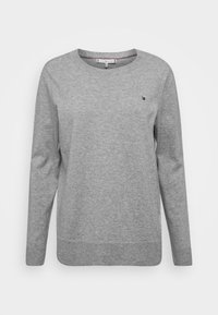 Sudadera gris de cuello redondo con mangas largas, hecha de una tela texturizada, que presenta un pequeño detalle del logo en el pecho y puños y dobladillo acanalados.