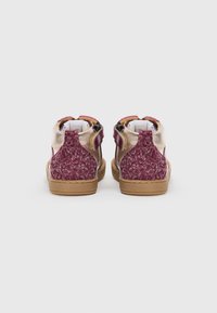 Høye sneakers med en teksturert bordeauxfarge på overdelen og gullfargede detaljer. Sålen er laget av brunt gummi med et mønster for bedre grep.