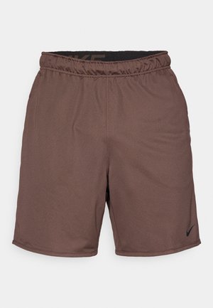Calções de desporto castanhos com uma cinta elástica, apresentando um tecido texturizado e um pequeno logotipo preto da Nike no canto inferior direito.
