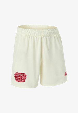 Pantalones cortos deportivos de color crema hechos de tela transpirable, con un logo rojo de Bayer Leverkusen y un logo de New Balance en rojo en el lateral.