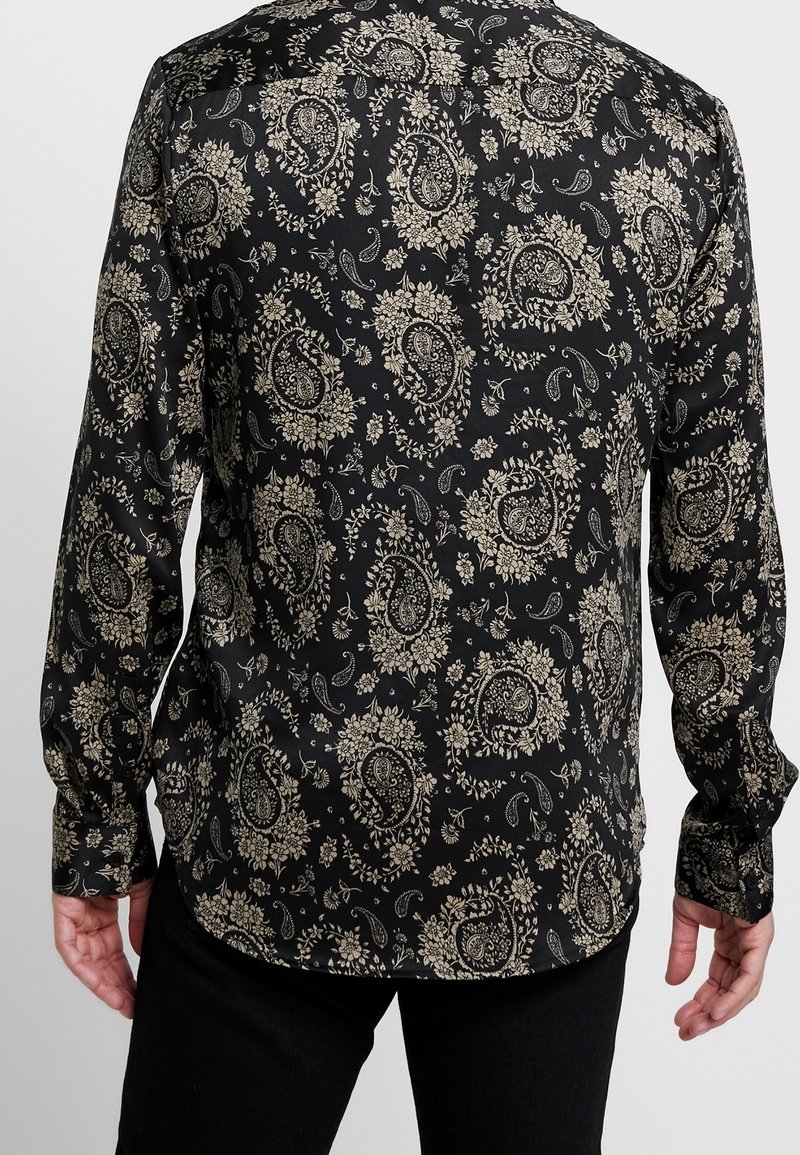 Černá košile s dlouhými rukávy s paisley a květinovým vzorem ve zlaté barvě, s rozhaleným límečkem a knoflíkovými manžetami, hladká textilie.