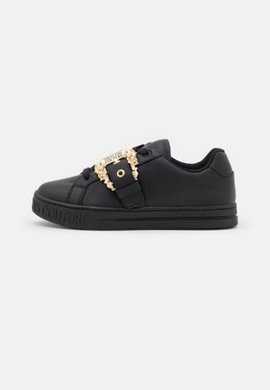 Czarny niski sneaker z wytłoczonym napisem na podeszwie oraz złotą ozdobną klamrą z logo "Versace Jeans Couture".