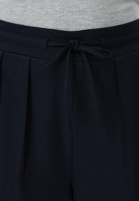 Σκούρο μπλε παντελόνι με πιέτες μπροστά και κορδόνι στη μέση, σε συνδυασμό με ανοιχτό γκρι ριμπ τοπ.