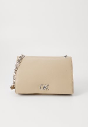 Beige kabelka z umělé kůže s elegantním obdélníkovým tvarem, stříbrným řetízkovým popruhem a výrazným logem značky na přední straně.