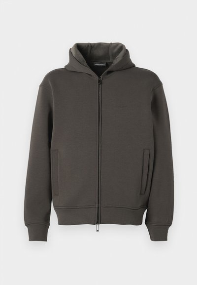 Sudadera con capucha en gris oscuro, hecha de tejido suave. Cuenta con un cierre de cremallera de longitud completa, dos bolsillos frontales y puños y dobladillo de canalé.