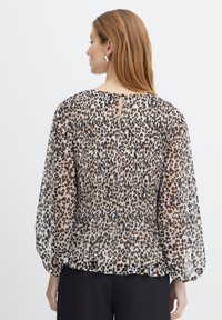 Permatomas marškinis su surinktu nugara, su leopardo raštu rudoje ir juodoje spalvose ant šviesaus fono, ir mažu raktų skylutės iškirpime.