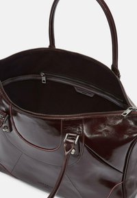 Bordowa skórzana torba o błyszczącym wykończeniu, z dwiema górnymi uchwytami i zamkiem błyskawicznym. Wnętrze wyłożone czarną tkaniną, z kieszenią na zamek.