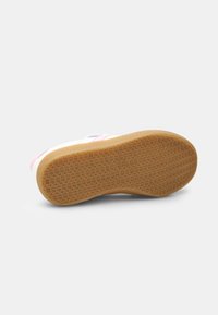 Sneaker outsole with a textured, rubber design; features a gum color with circular patterns for traction and durability.