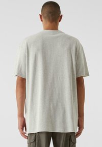 Lysegrå bomuld t-shirt med afslappet pasform, korte ærmer og lige kant. Bagsiden viser en sømløs krave og en glat tekstur.