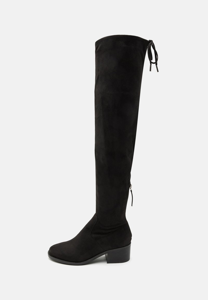 Botas negras por encima de la rodilla hechas de suave ante, con punta redonda, un tacón bajo en bloque y lazos ajustables en la parte superior para un mejor ajuste.