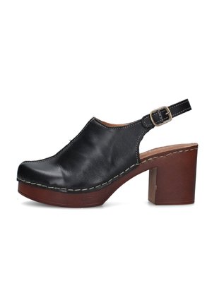 Zoccolo in pelle nera con tacco con plateau in legno marrone e fibbia regolabile alla caviglia, vista laterale su sfondo bianco.