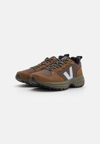 Brown suede and mesh sneakers with black rubber soles, grey accents, and patterned laces. Designed for outdoor use with a robust structure.