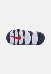Nike sportbačių padas, turintis mėlyną gumos pagrindą, baltą tekstūruotą vidurinį padas ir raudoną Nike swoosh akcentą. Išskirtinis bangos formos raštas visame paviršiuje.