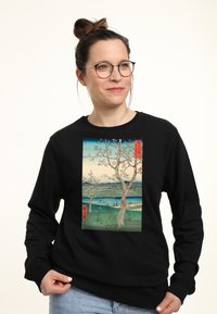 Felpa nera con stampa frontale di un'opera che raffigura un albero e un paesaggio con montagne e acqua. Materiale in cotone, vestibilità rilassata.
