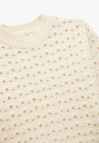 Sweter w kolorze kremowym z dzianiny, z teksturowanym wzorem otwartych dziur i ściągaczem przy okrągłym dekolcie. Miękki, lekki i oddychający materiał.