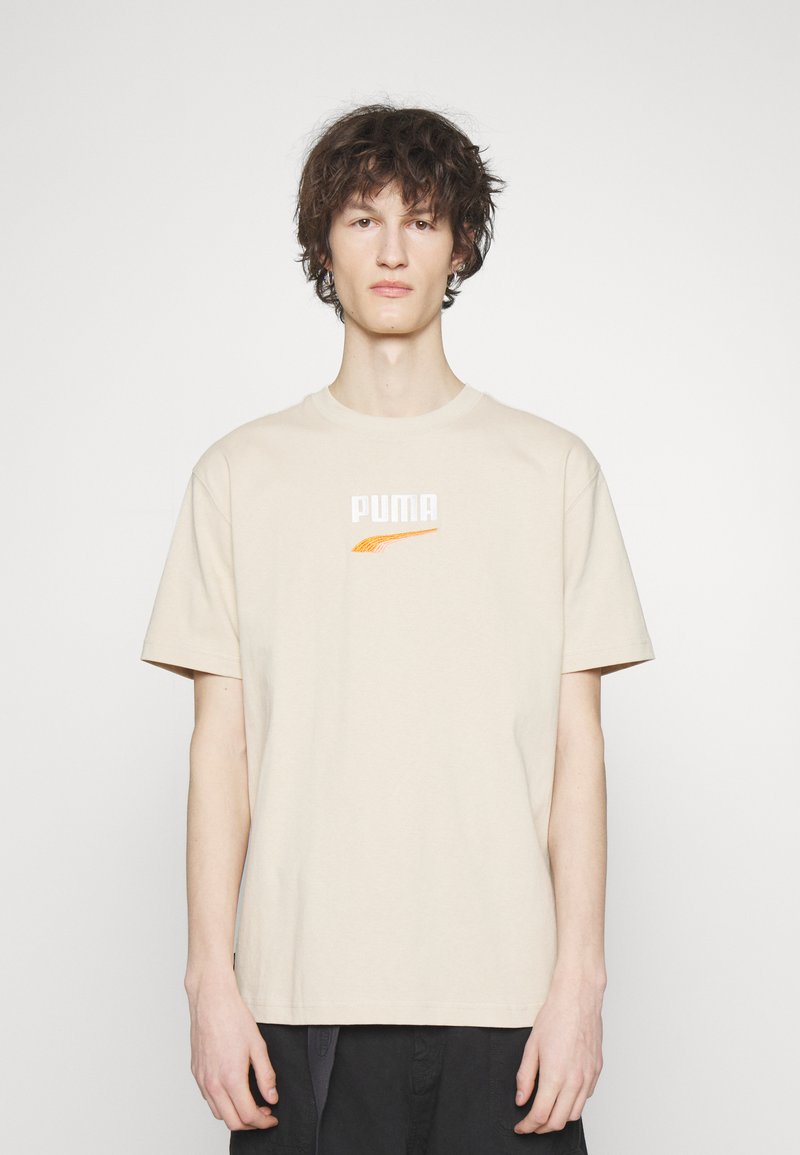 Beige katoenen T-shirt met korte mouwen en een ronde hals. Voorzien van een geborduurd oranje en wit "PUMA" logo op de borst.