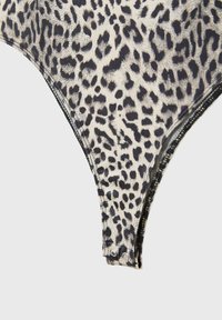 Body en imprimé léopard avec des couleurs noir et crème. Tissu extensible avec des détails de fermeture à pression sur le bas. Bords nets et lisses.