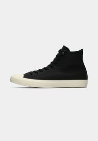 Sneaker alte nere in tela con suole in gomma bianca, punta arrotondata e occhielli neri. Design semplice con tomaia testurizzata.