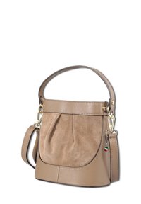 Tan leren en suède handtas met een kort handvat, afneembare schouderband en een klein vlag sleutelhanger detail op een witte achtergrond.